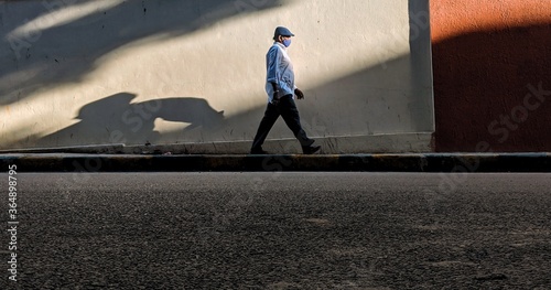 Man with a mask walks on the street going solo walk