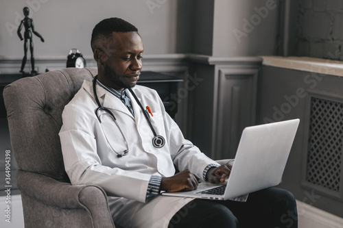 dark-skinned doctor talking on Skype zoom with a laptop photo