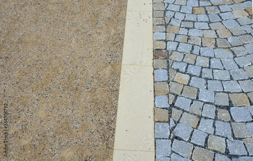 a new park path made of irregular cubes, folded with a side channel for draining water from the road surface. granite stones of gray and brown color in places the path is enclosed black metal railing photo