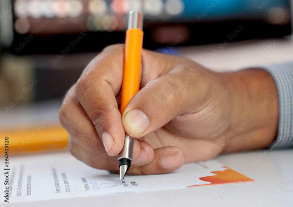 Closeup of Businessman signs documents with a pen sitting at the desk Closeup of Businessman signs documents with a pen sitting at the desk