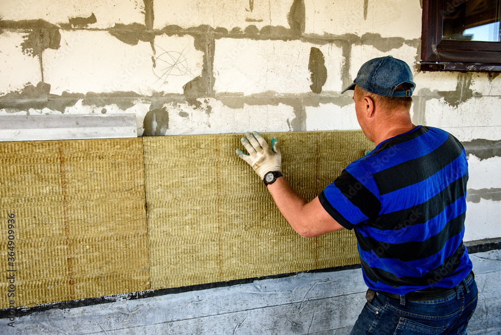 Worker insulates the house with mineral wool slabs. Internal thermal insulation of walls with mineral wool.