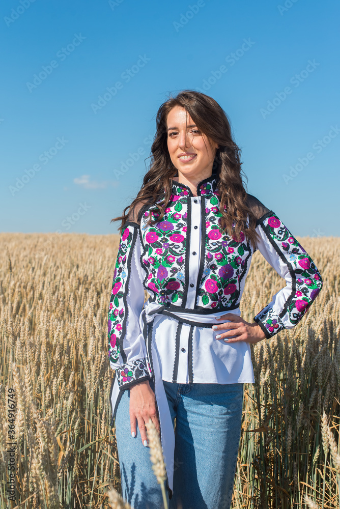 A young, pretty, pretty girl in a Ukrainian folk traditional shiny costume in a golden wheat field. A young, pretty, pretty girl in a Ukrainian folk traditional shiny costume in a golden wheat field.