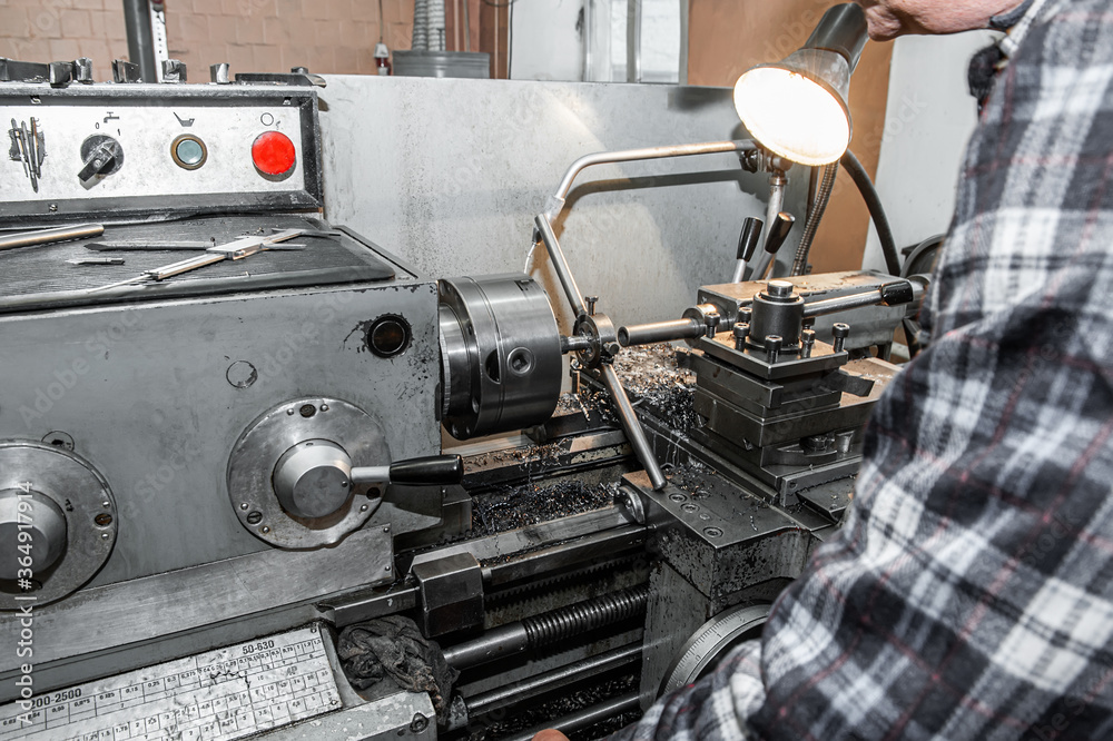 Fototapeta premium master grinds metal product. The old Metalworking machine, manufactured in the middle of the last century, is still in good condition.