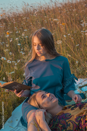Two female friends in field and have a picnic summer outdoors.