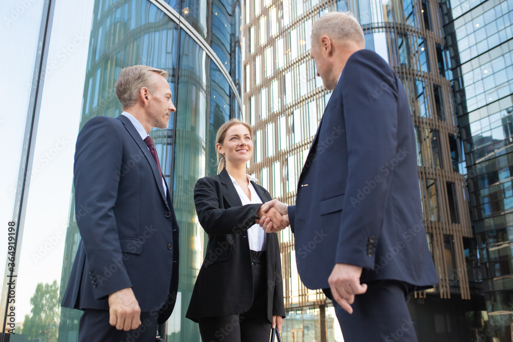 Φωτογραφία Positive confident business people meeting in city, shaking hands near office building