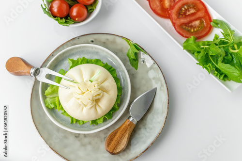 Burrata with Cutlery top view. dinner with tomato and spinach salad with Italian Buratto cheese. The concept of healthy Mediterranean food photo