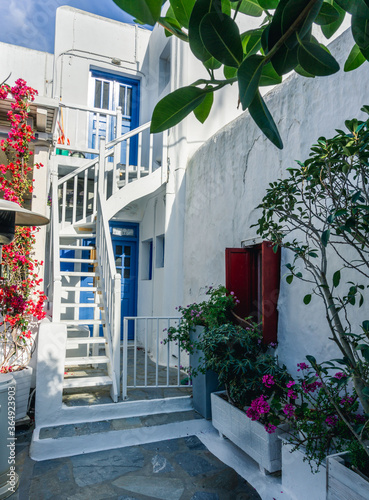 Fototapeta Naklejka Na Ścianę i Meble -  Colorful houses, blue and red doors and windows and lots of flowers in the old town of Mykonos Island, Greece.
