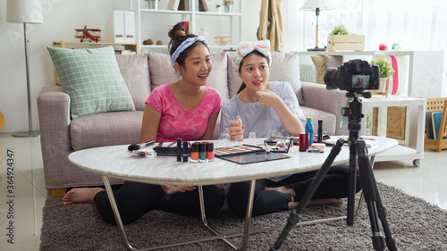 Portrait two asian blogger women review giveaway makeup gift to fan while recording video makeup cosmetic at home living room. online influencer vlogger on social media live streaming concept