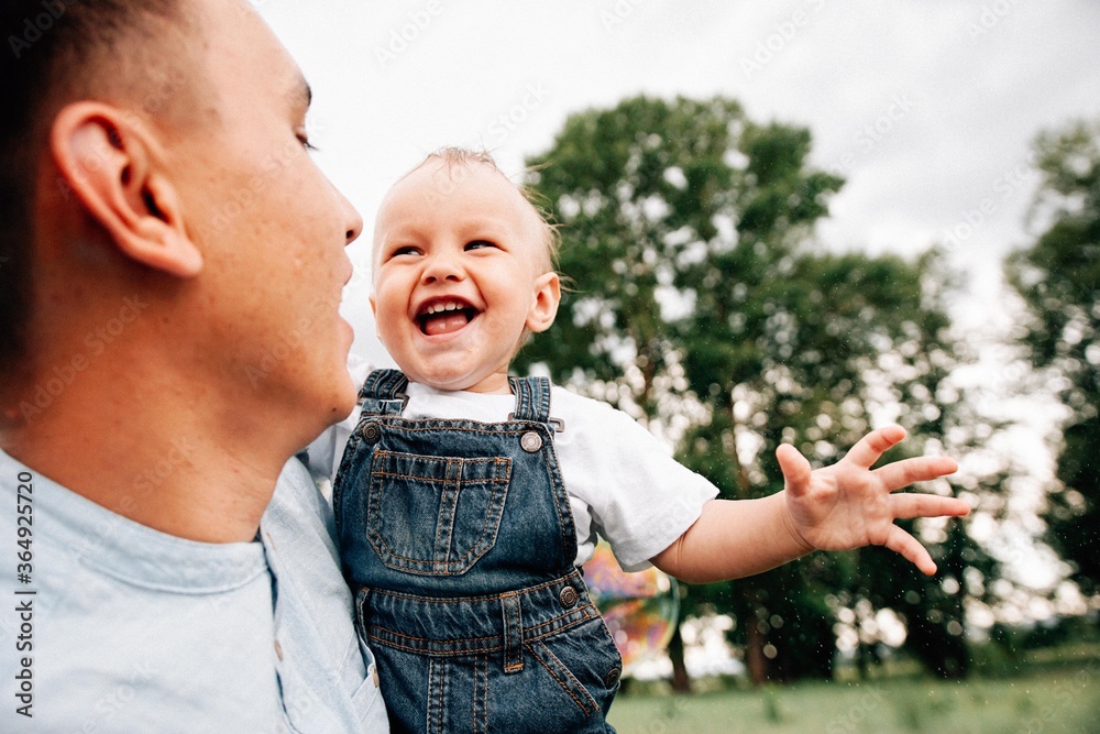 Fototapeta premium Mother and father have a good time with his little son outdoor at summertime