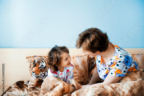 Young active mother and her little daughter having fun together at home in bedroom wearing funny pajamas. fanily time. Mother and daughter spending time together photo