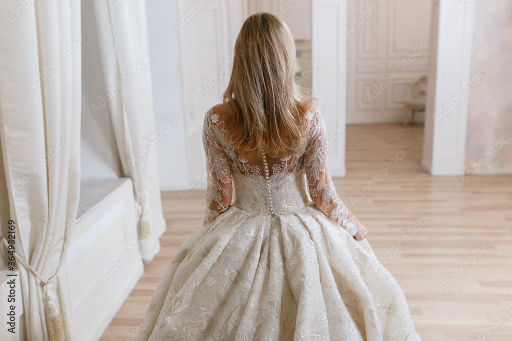 Fototapeta premium Bride in a magnificent wedding dress posing in a light interior photo studio. Vintage design