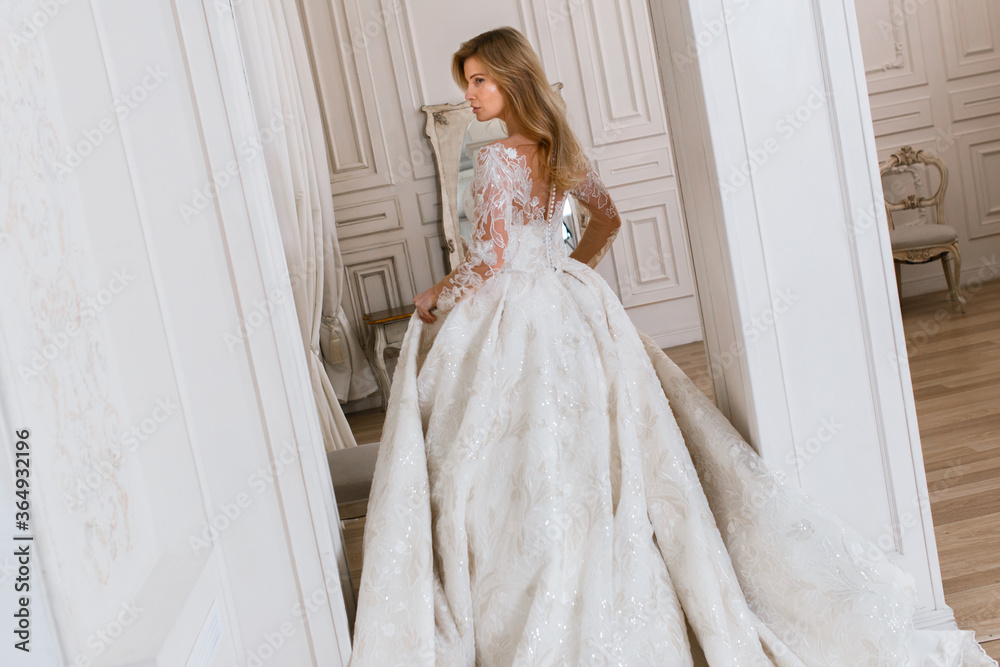 Bride in a magnificent wedding dress posing in a light interior photo studio. Vintage design Bride in a magnificent wedding dress posing in a light interior photo studio. Vintage design