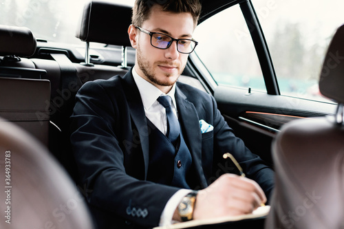 Young businessman signing documents in luxury car