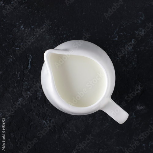 Fotomurale Whit milk jug with milk on a black background, top view.