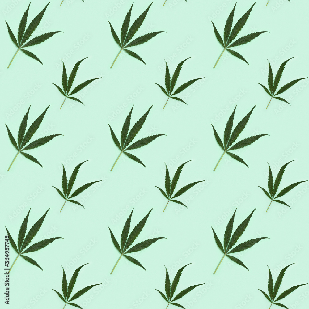 Fototapeta premium Seamless regular creative pattern with natural green leaves from Cannabis plant. Printing on fabric, wrapping paper.