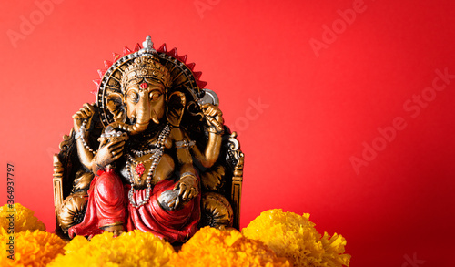 Happy Ganesh Chaturthi festival  Bronze Ganesha statue and Golden texture with flowers  Ganesh is hindu god of Success.