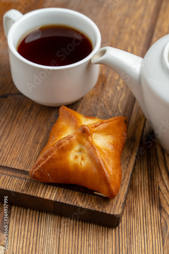 Single russian stuffed pirozhok with black tea on wooden table photo