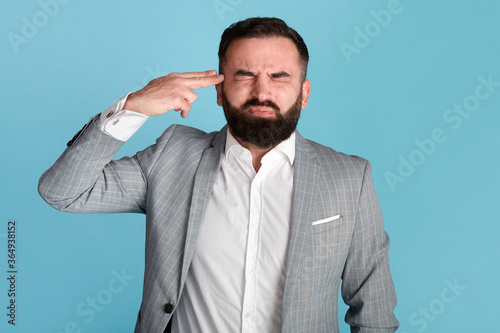 Fotografi Stressed businessman pointing fingers to his head like gun, wanting to shoot him