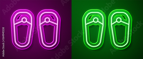 Glowing neon line Flip flops icon isolated on purple and green background. Beach slippers sign. Vector.