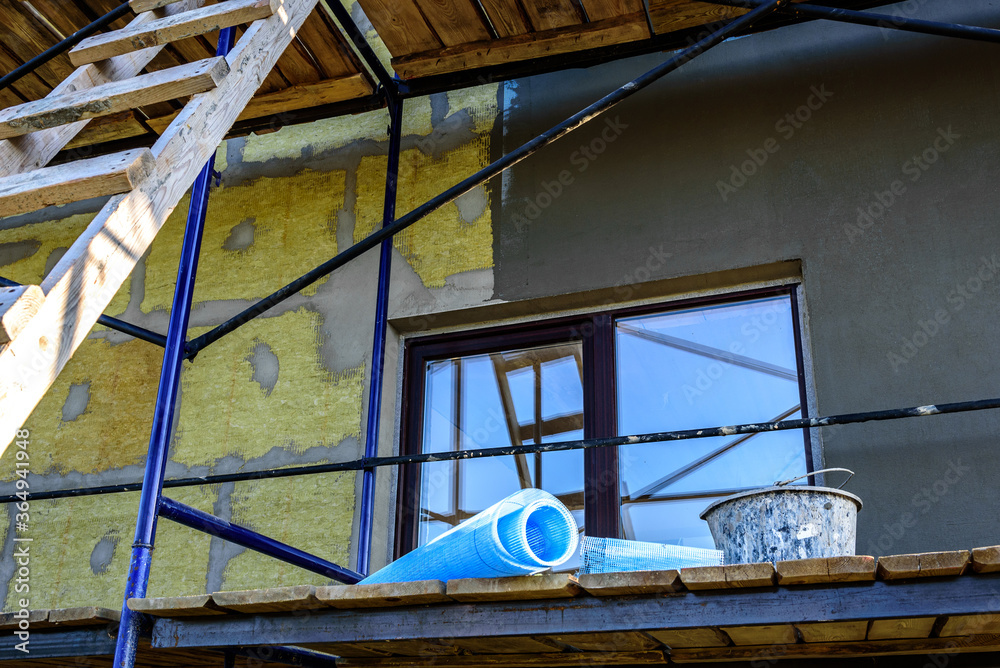 Obraz premium Applying construction glue layer on insulated wall for covering fiberglass reinforcing mesh on mineral wool.