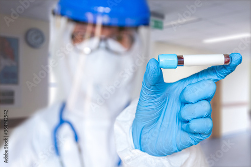 Female doctor or nurse in protective suit holding a positive blood test