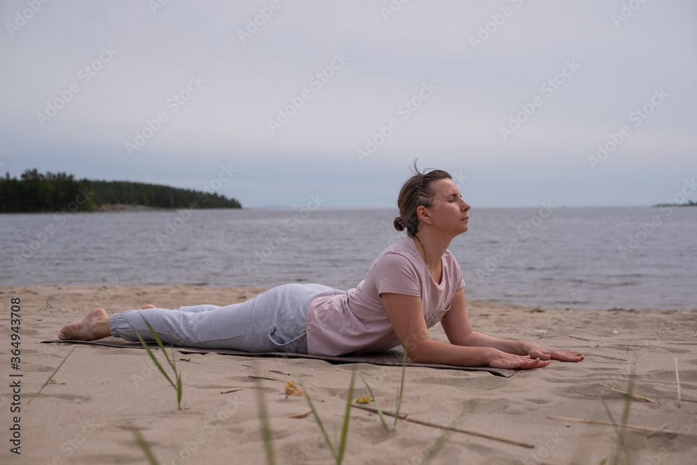 Woman doing Cobra Yoga Stretch on yoga mat in beach