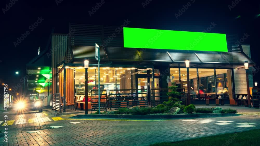 Green screen billboard or wide display on a building of express service cafe. Entertainment, consumerism and chroma concept. Visitors come in and out at. cars drive up for their portion of fast food.