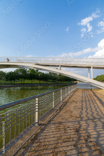 Vertical view of a bridge and fence  over canal with blue summer sky  in Juan Carlos I park in Madrid  Spain