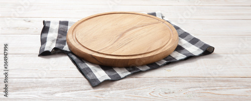 Empty pizza board and tablecloth on wooden deck table with napkin