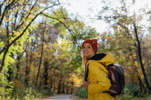 Woman tourist with backpack walking in autumn forest. Active lifestyle, travel concept 