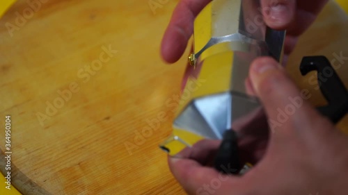 Men's hands unscrew parts from aluminum geyser coffee maker