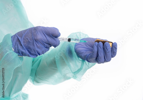 Doctor with gloves and mask preparing vaccine on white background