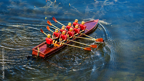 
A toy wooden boat, in the boat toy people, work with oars and sail on the water.