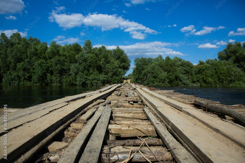 Damage bridge. Old wooden bridge through the river with green trees on the banks