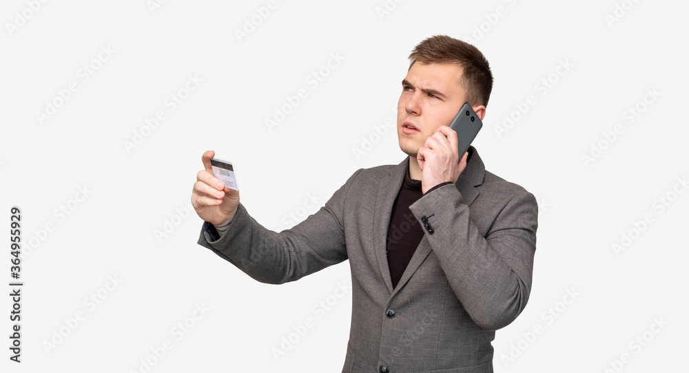Bank fraud. Scam call. Doubtful business man with credit card talking on phone isolated on white background. Bank fraud. Scam call. Doubtful business man with credit card talking on phone isolated on white background.