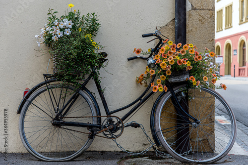 Rusty old bicycle decorated with colorful flowers against a hous wall in Murten, Switzerland photo