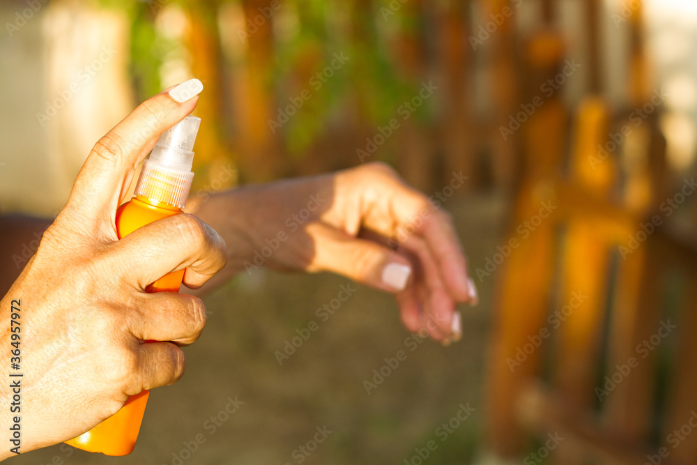 Mano femenina con spray de cosméticos al aire libre. Vista de frente y de cerca Mano femenina con spray de cosméticos al aire libre. Vista de frente y de cerca