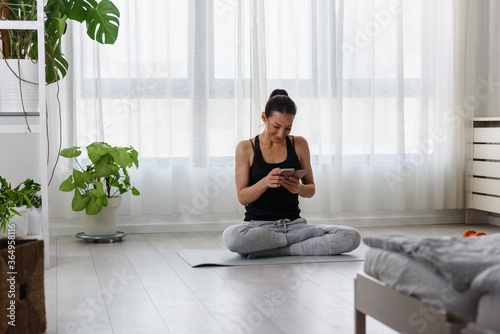 Young sporty woman using smartphone after exercise at home