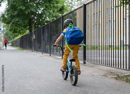 A boy with a school backpack goes to school on a Bicycle. Back to school.