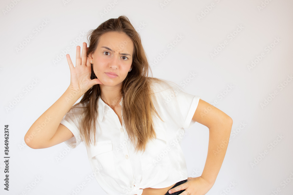 Beautiful young girl in white shirt making the listening gesture Beautiful young girl in white shirt making the listening gesture