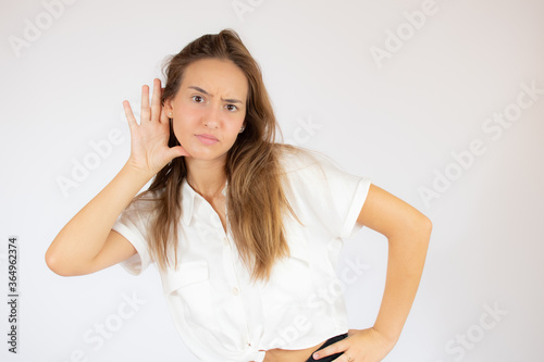 Beautiful young girl in white shirt making the listening gesture