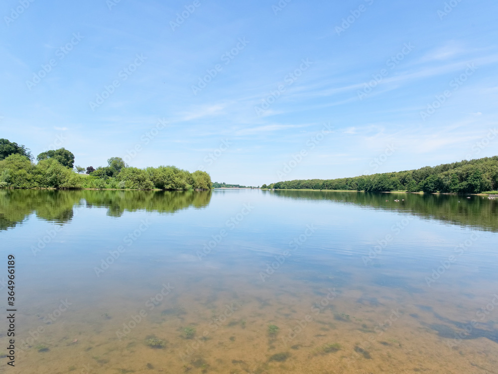 Still water of Staunton Harold Reservoir under a blue summer sky