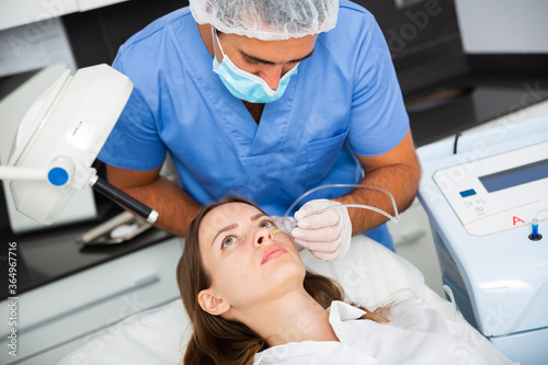 Portrait of female patient during cosmetology procedure in beauty clinic, getting carbon dioxide injections for face skin rejuvenation