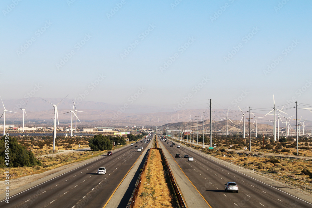 a wide full angle view overlooking multiple lanes of california freeway interstate highway traffic with desert and blue sky