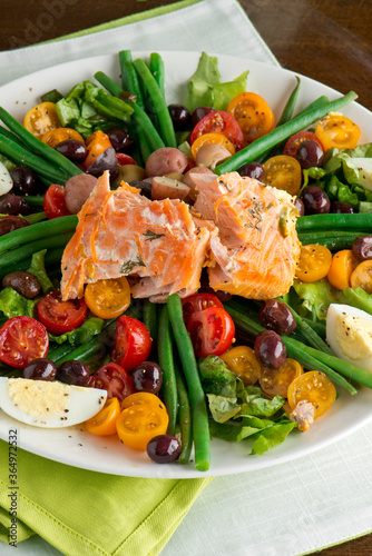 Nicoise salad. Romaine, cherry tomatoes hard boiled eggs, baby purple potatoes. green beans and grilled salmon tossed with olive oil and salt and pepper