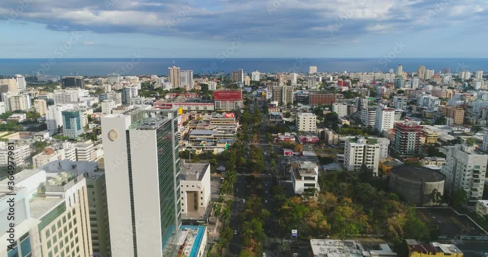 Establishing flight above downtown city center Santo Domingo skyscrapers, main street, and commercial buildings towards blue ocean sea, Dominican Republic, overhead aerial approach Establishing flight above downtown city center Santo Domingo skyscrapers, main street, and commercial buildings towards blue ocean sea, Dominican Republic, overhead aerial approach