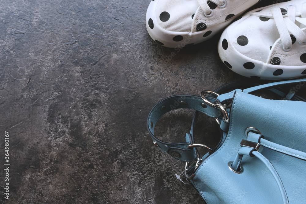 Obraz premium Women bag and white sneakers on a wooden background with space for text. Women's bag and shoes.