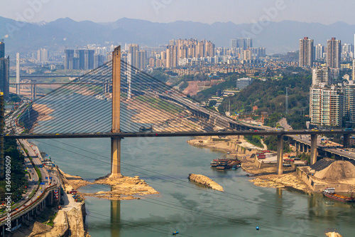 Chongqing, China - March 20, 2018: Top view of the  Jialing River in the Chinese city of Chongqing. Bridges, city blocks, mountains. Sunny day in the metropolis.