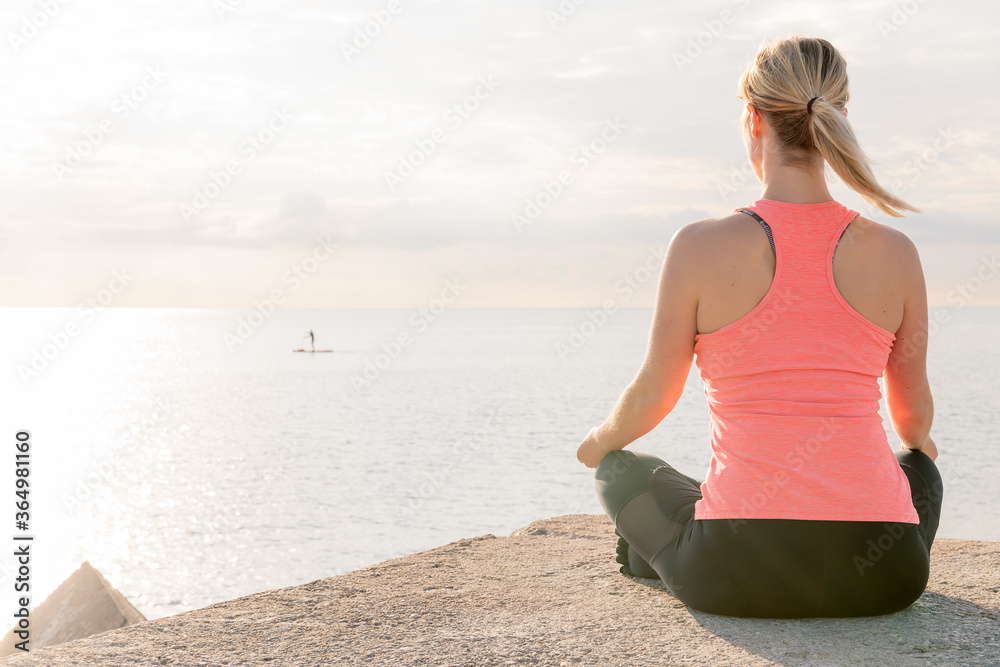 back of a blonde woman practicing yoga at sunrise back of a blonde woman practicing yoga at sunrise