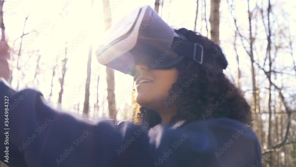 4K video clip of beautiful mixed race African American girl teenager female young woman using virtual reality VR headset in a forest woodland environment 4K video clip of beautiful mixed race African American girl teenager female young woman using virtual reality VR headset in a forest woodland environment